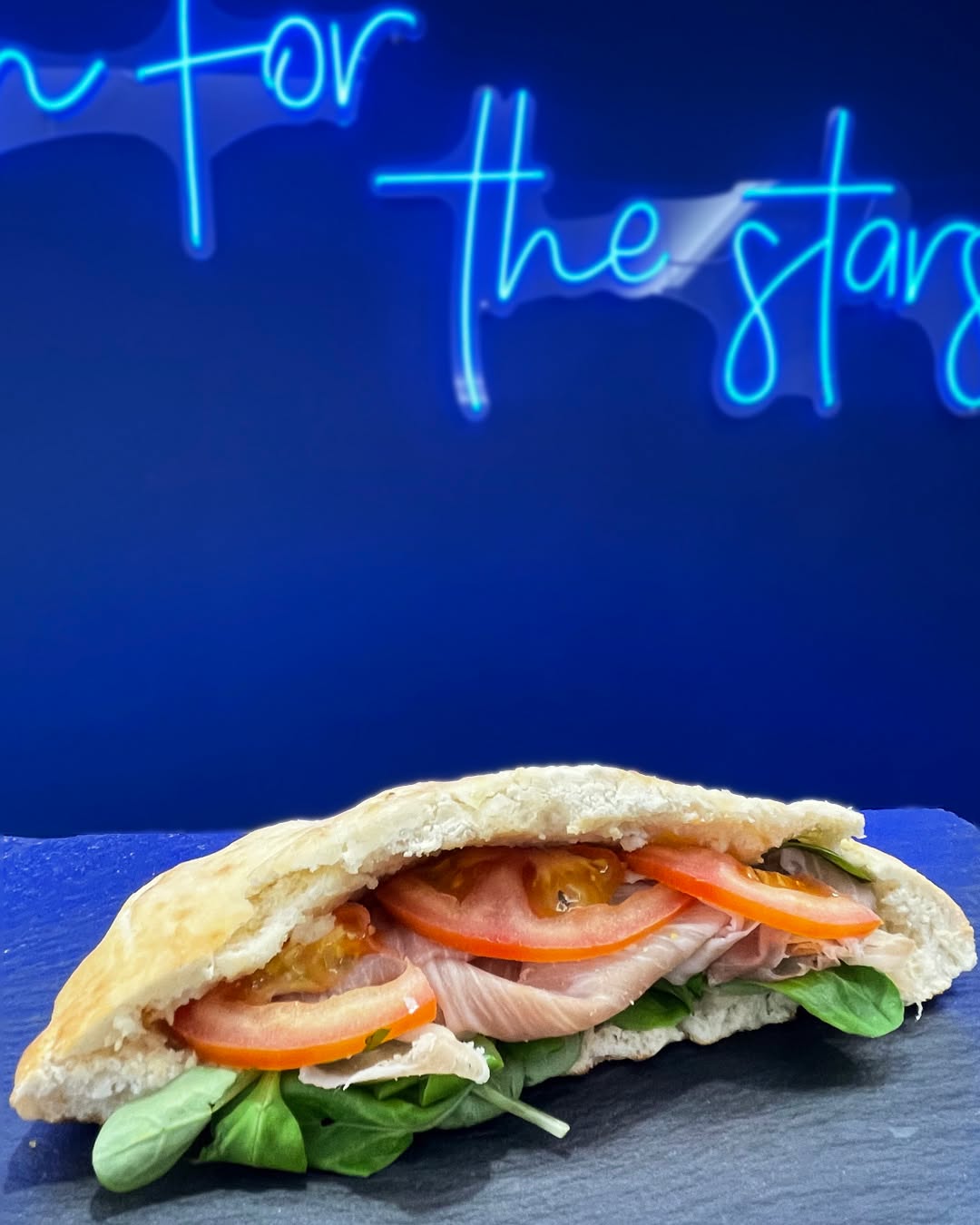 Panino gourmet servito su tavolo blu al Deep Space Lounge.